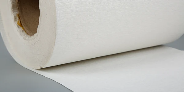 A roll of white automotive filter paper with a creped surface.
