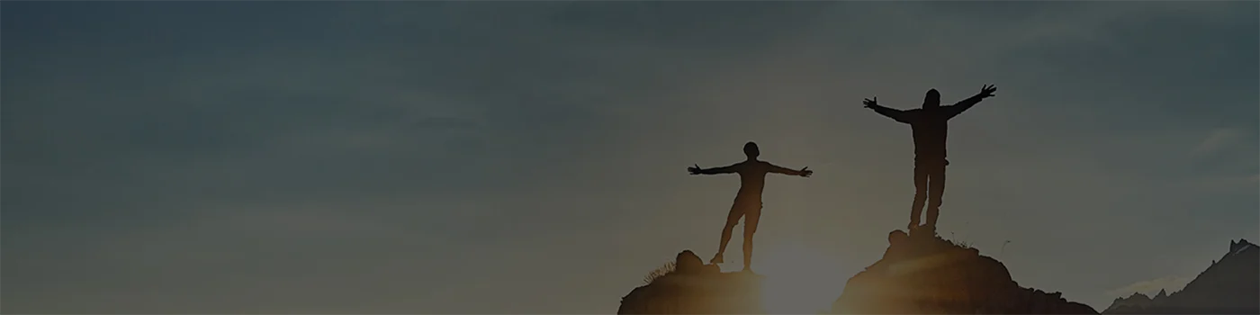 Two people are embracing the sunrise on a mountain.