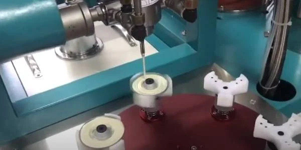 The glue machine is bonding metal end cap and filter element together.