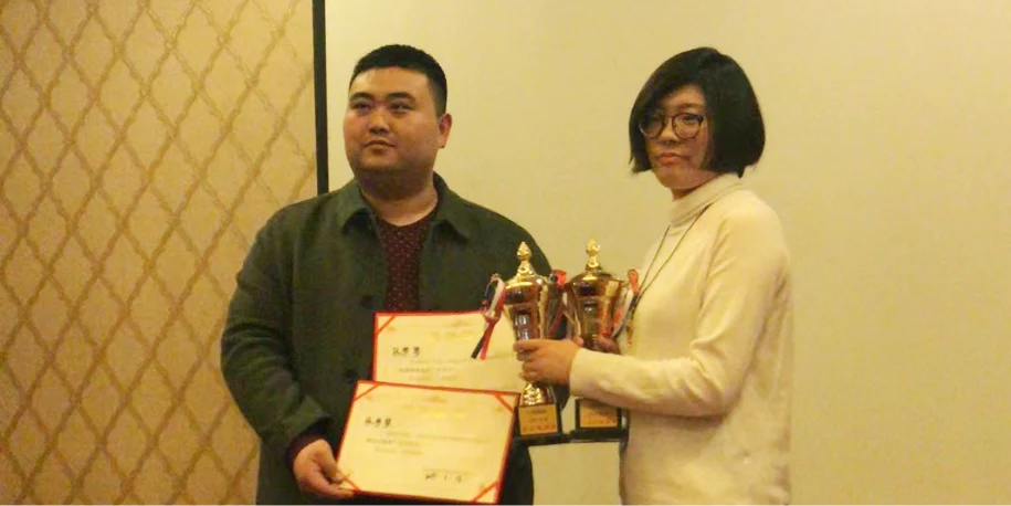 A group photo of 2 persons receiving a reward.