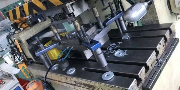 The stamping machine is making metal end caps.